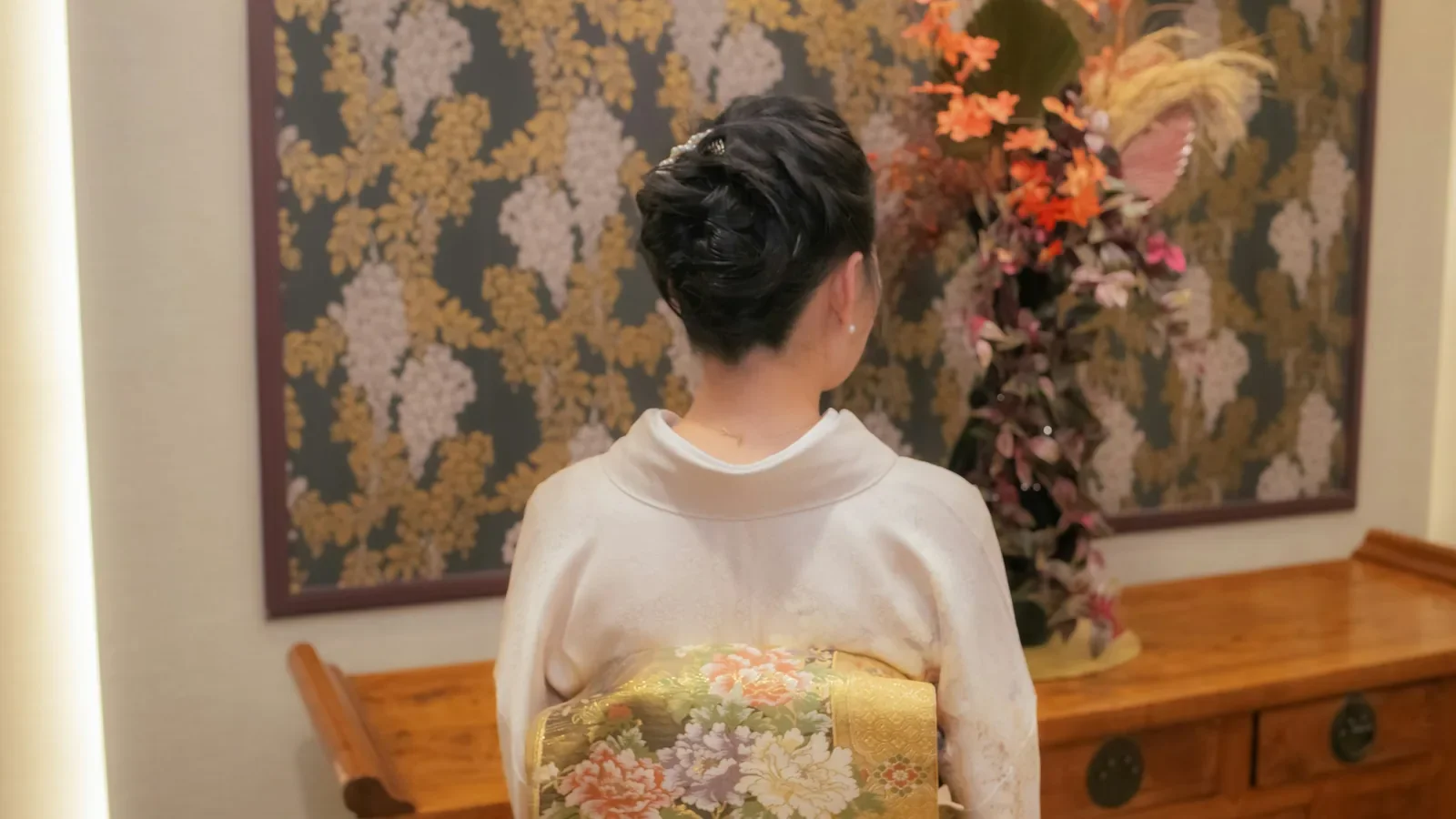 淡い色の着物に、花の柄の袋帯を結んだ後ろ姿